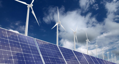 Wind turbines on a cloudy blue sky over solar panels