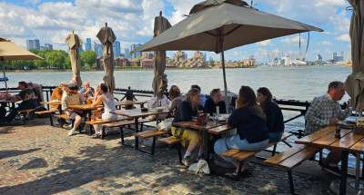 People seated by the River Thames on benches with sun brollies